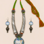 Kashish handcrafted Indian statement neckpiece set with oxidised silver finish, green and orange threadwork, cow and calf pendant, and matching earrings