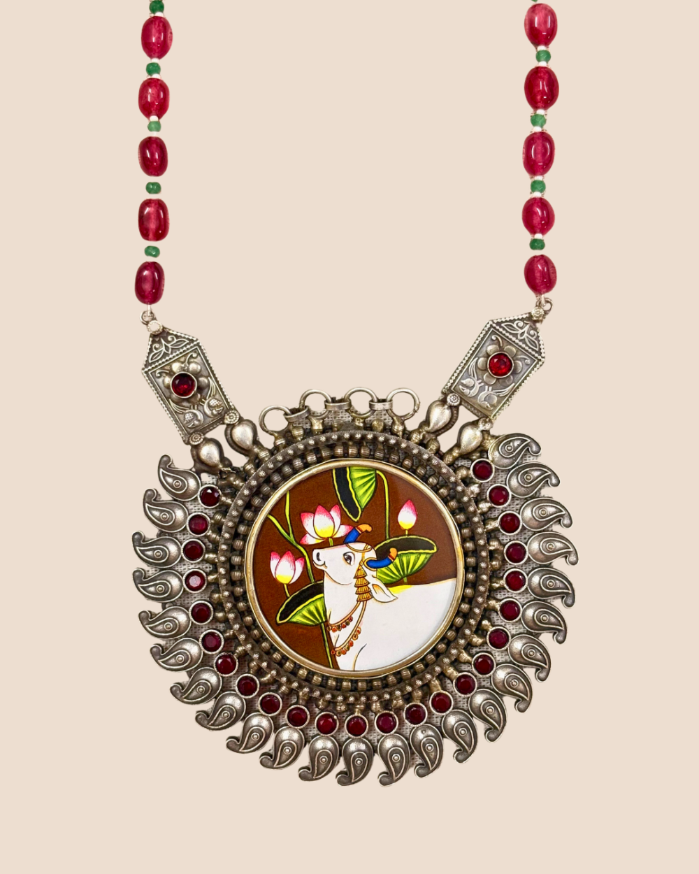 Close view of Aabha neckpiece pendant with engraved side plaques, red stones and oxidised silver paisleys