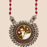 Close view of Aabha neckpiece pendant with engraved side plaques, red stones and oxidised silver paisleys
