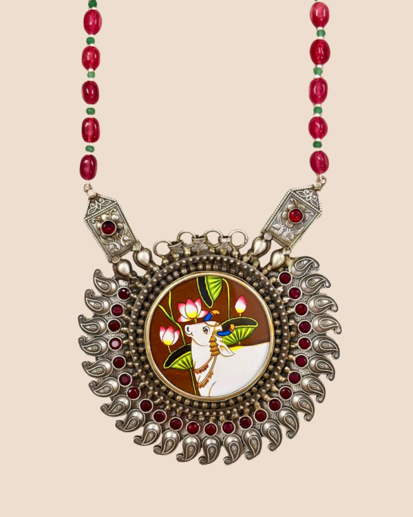 Close view of Aabha neckpiece pendant with engraved side plaques, red stones and oxidised silver paisleys